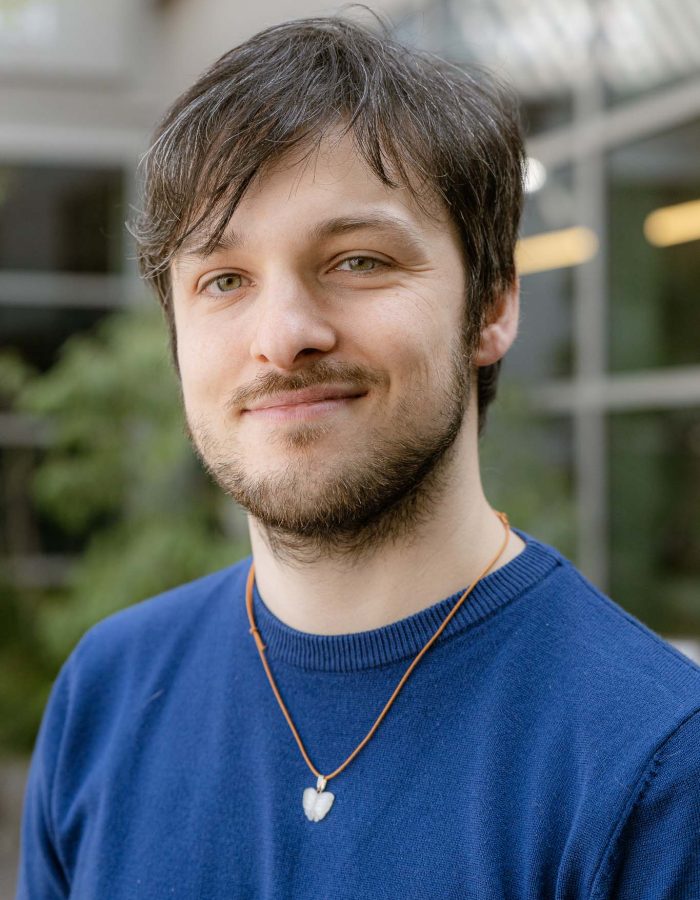 davide riccio, guarda l'osservatore con una maglia azzurra e un ciondolo bianco